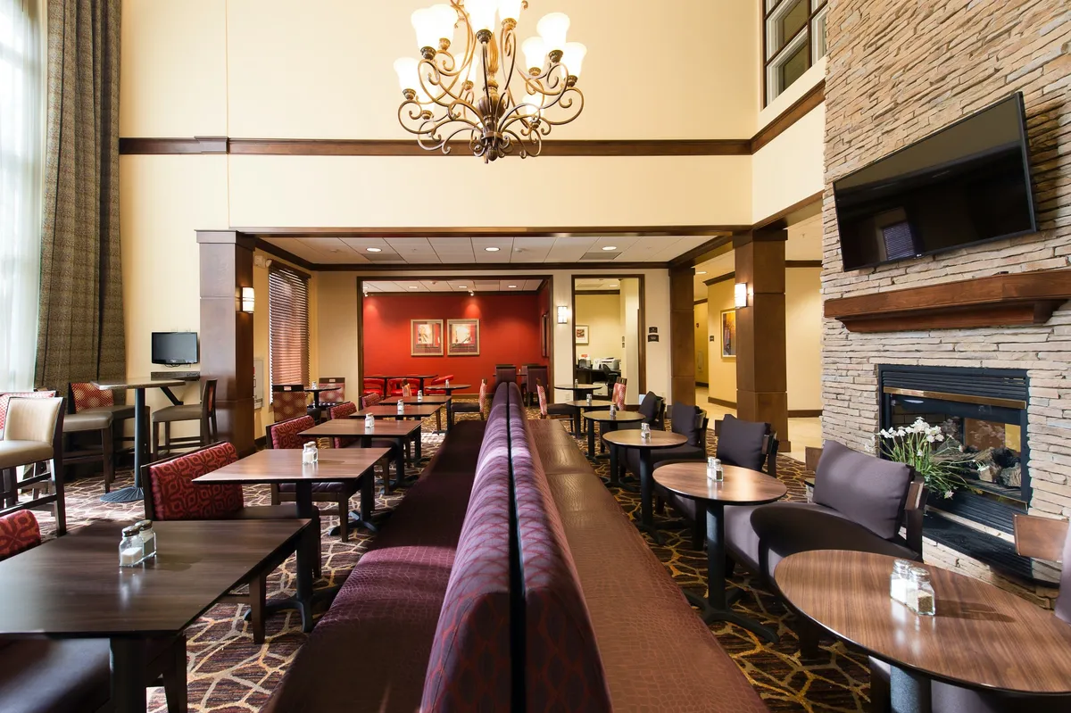 A stylish social lounge with a striking chandelier, inviting fireplace, and comfortable seating arrangements. The atmosphere is warm and welcoming, ideal for evening socials, casual meetings, and relaxed gatherings.